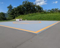 グレーに塗り替えた土間とオレンジの円・外周ラインが仕上がった相模原市のヘリポートのコンクリート土間
